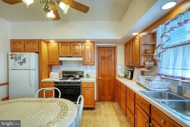 kitchen featuring white fridge, tasteful backsplash, gas stove, ceiling fan, and sink