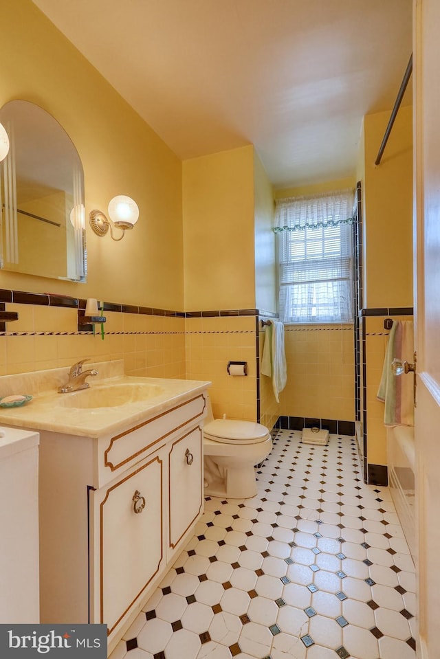 bathroom featuring tile walls, toilet, and vanity