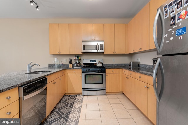 kitchen featuring sink, light brown cabinetry, dark stone counters, and appliances with stainless steel finishes