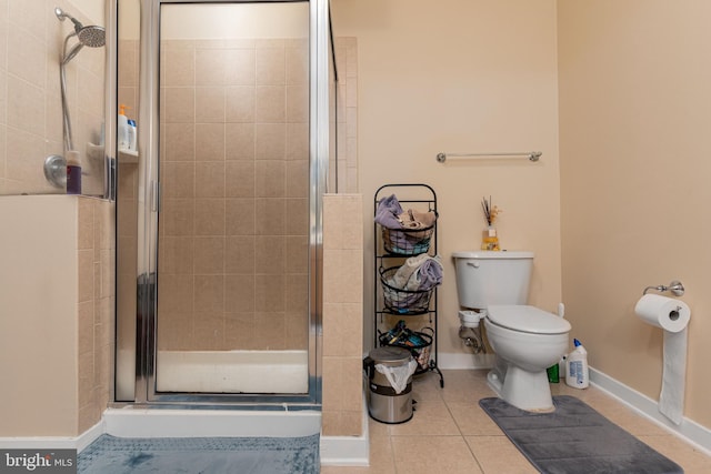 bathroom featuring toilet, a shower with door, and tile patterned flooring