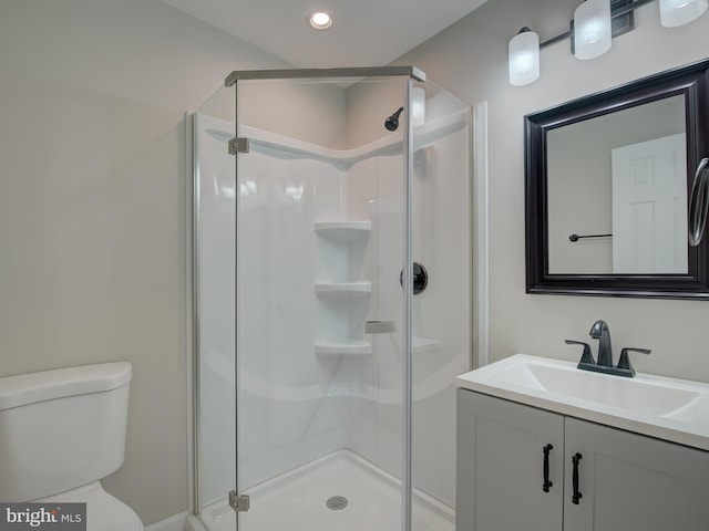 bathroom featuring toilet, vanity, and a shower with shower door