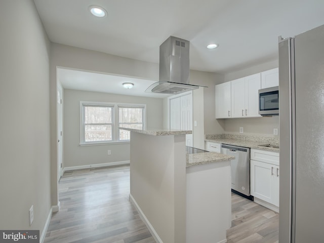 kitchen featuring white cabinetry, appliances with stainless steel finishes, a center island, and island range hood