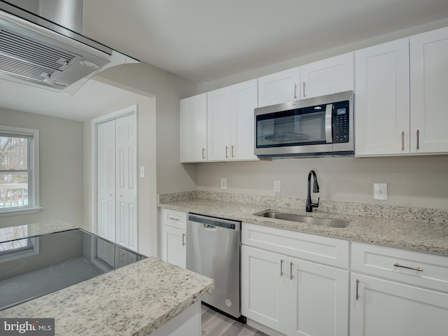 kitchen featuring extractor fan, appliances with stainless steel finishes, white cabinetry, sink, and light stone countertops