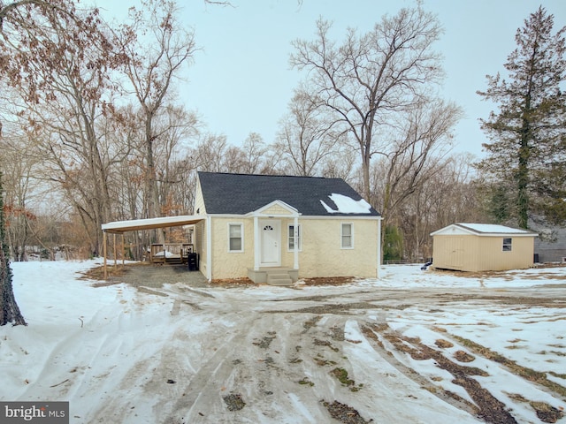 view of front of property featuring a carport and a shed