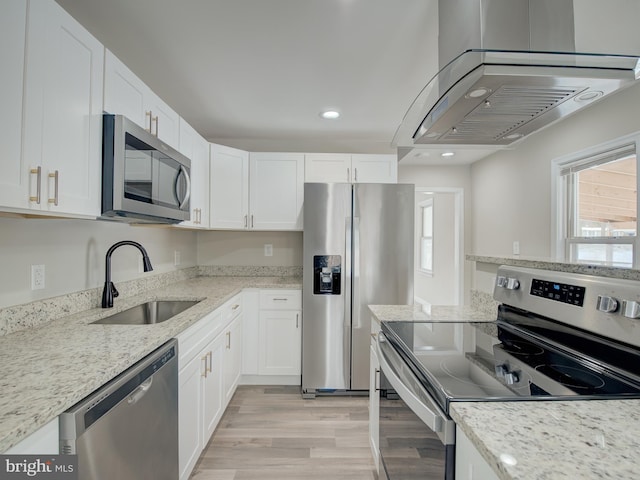 kitchen featuring sink, island range hood, white cabinets, and appliances with stainless steel finishes