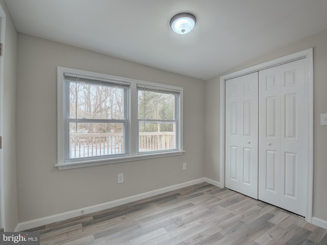 unfurnished bedroom with light hardwood / wood-style flooring and a closet