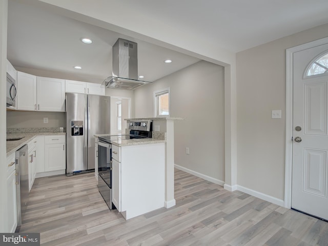 kitchen featuring white cabinetry, light stone counters, appliances with stainless steel finishes, island exhaust hood, and light hardwood / wood-style floors