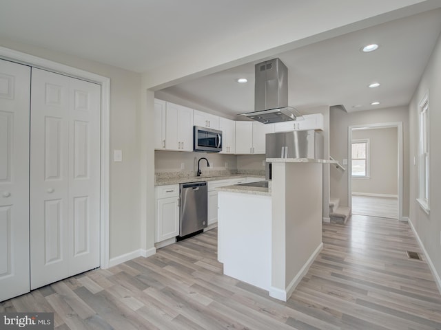 kitchen with white cabinetry, stainless steel appliances, a center island, island range hood, and light hardwood / wood-style floors