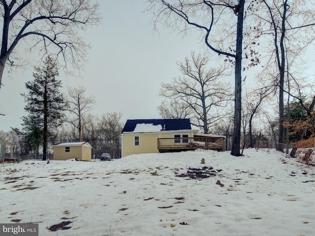 view of snow covered exterior with a wooden deck and a shed