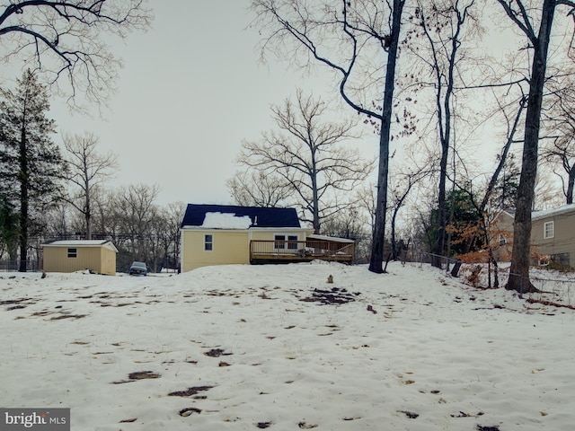 snowy yard with a wooden deck and a storage shed