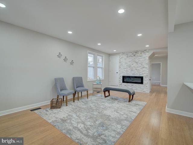 sitting room featuring a large fireplace and light wood-type flooring