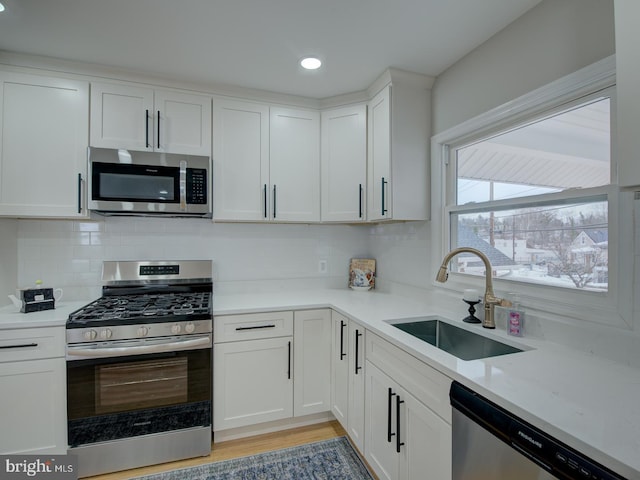 kitchen with light stone counters, appliances with stainless steel finishes, sink, and white cabinets