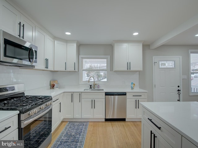 kitchen featuring appliances with stainless steel finishes, light hardwood / wood-style floors, sink, and white cabinets