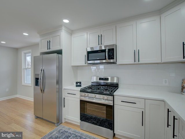 kitchen featuring backsplash, appliances with stainless steel finishes, light hardwood / wood-style flooring, and white cabinets