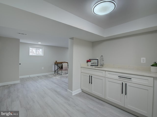 bar featuring sink, white cabinets, and light hardwood / wood-style flooring