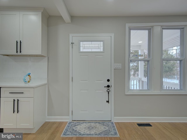 foyer with beamed ceiling, light wood-type flooring, and a wealth of natural light