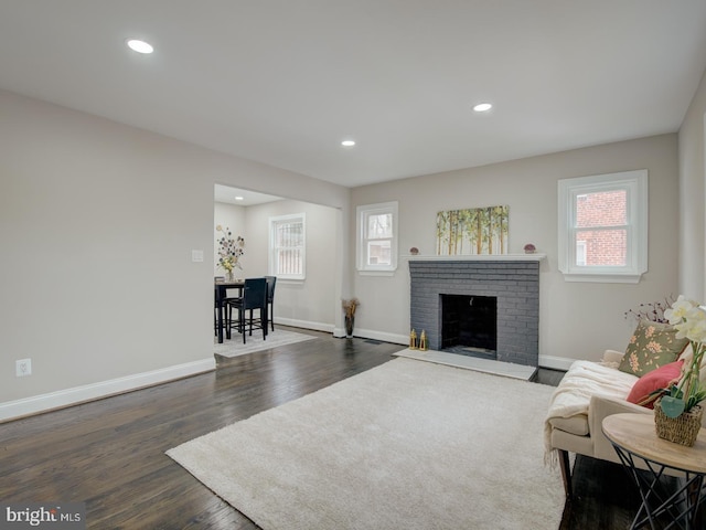 living room featuring a fireplace, a healthy amount of sunlight, and dark hardwood / wood-style flooring