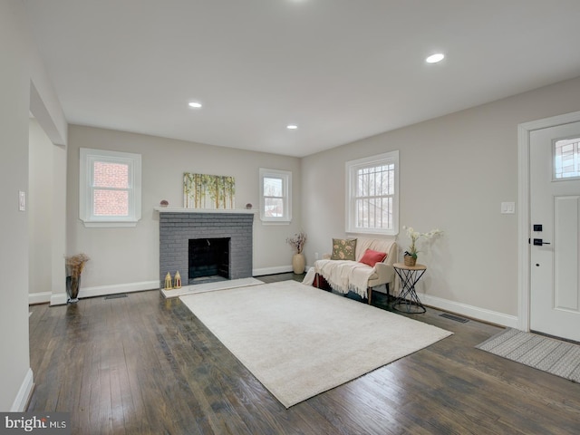 living room with dark hardwood / wood-style flooring and a brick fireplace