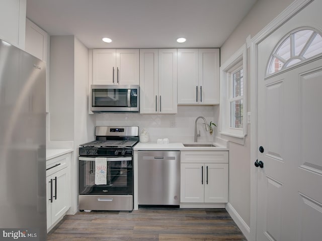 kitchen with white cabinetry, appliances with stainless steel finishes, sink, and wood-type flooring