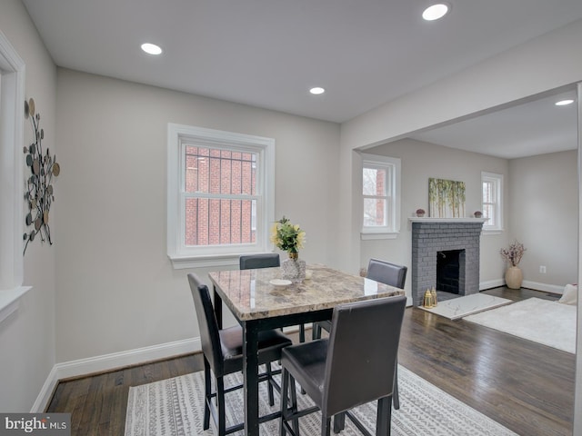 dining space with dark hardwood / wood-style flooring and a brick fireplace