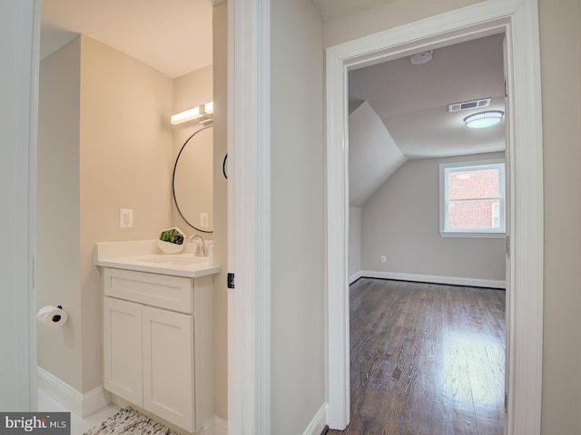 bathroom with vanity, hardwood / wood-style flooring, and lofted ceiling