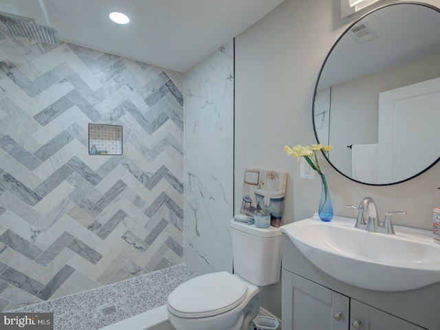 bathroom featuring vanity, tiled shower, and toilet