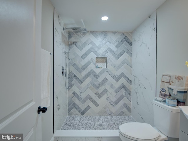 bathroom with a tile shower and toilet