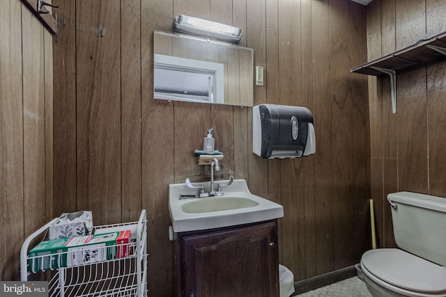 bathroom with toilet, wood walls, and vanity