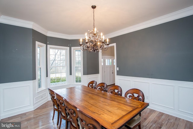 dining room with an inviting chandelier, ornamental molding, and light hardwood / wood-style flooring