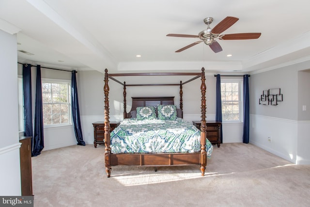 carpeted bedroom featuring ceiling fan, ornamental molding, and a raised ceiling