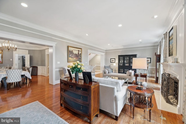 living room with crown molding, light hardwood / wood-style flooring, and a notable chandelier