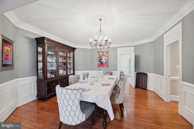 dining space featuring crown molding, hardwood / wood-style floors, and a chandelier