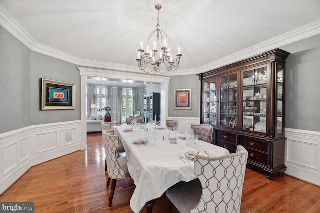 dining space featuring crown molding, wood-type flooring, and a notable chandelier