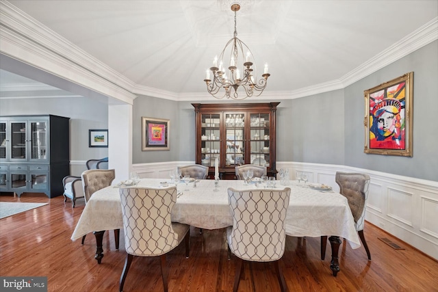 dining space featuring an inviting chandelier, ornamental molding, and hardwood / wood-style flooring