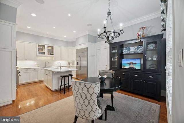 dining space featuring sink, light hardwood / wood-style flooring, and ornamental molding