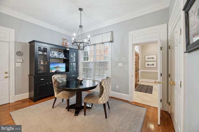 dining space featuring hardwood / wood-style floors, crown molding, and a chandelier