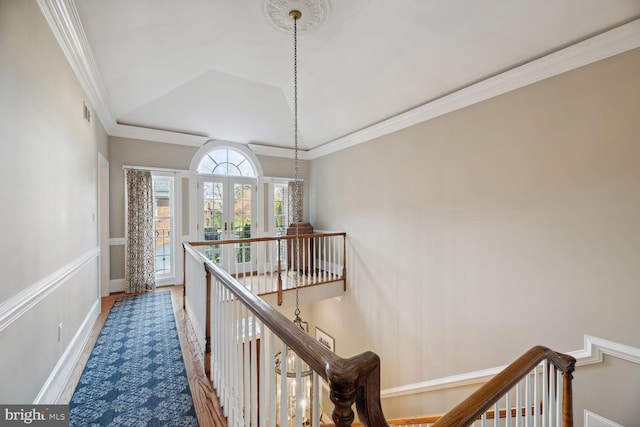 corridor with ornamental molding, vaulted ceiling, wood-type flooring, and french doors