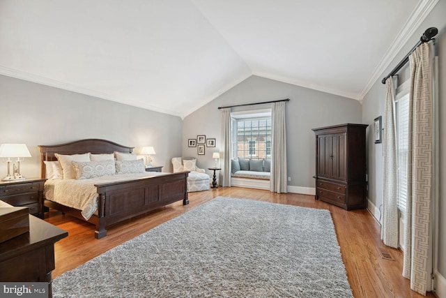 bedroom featuring light hardwood / wood-style flooring, ornamental molding, and vaulted ceiling