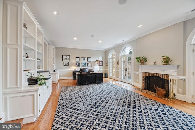 home office with crown molding, a fireplace, and light wood-type flooring