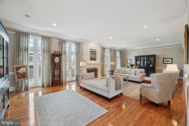 living room featuring a wealth of natural light, ornamental molding, and light wood-type flooring