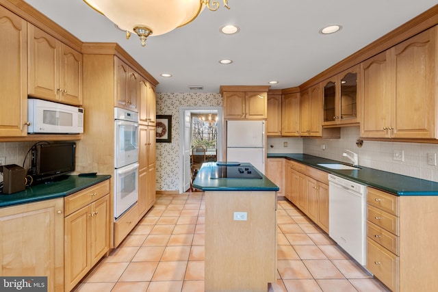 kitchen featuring a center island, dark countertops, a sink, white appliances, and wallpapered walls