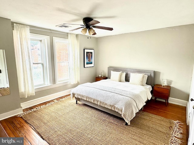 bedroom with a ceiling fan, visible vents, baseboards, and hardwood / wood-style floors