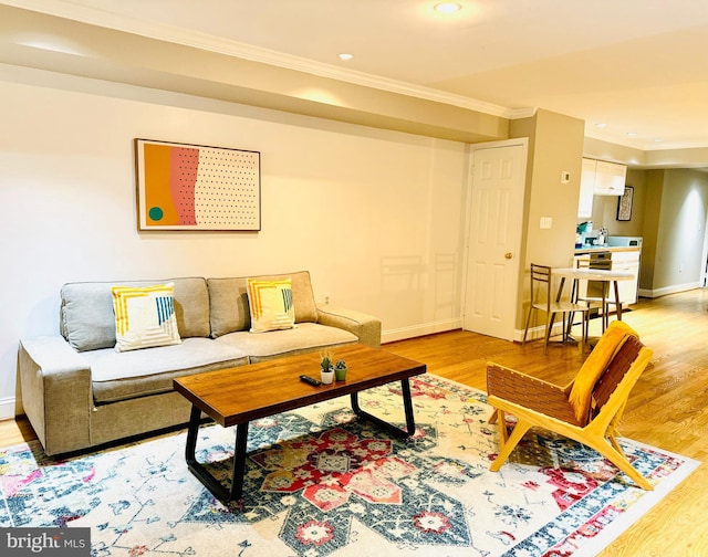 living room featuring light wood-style flooring, baseboards, crown molding, and recessed lighting