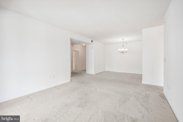 unfurnished room featuring an inviting chandelier and light colored carpet