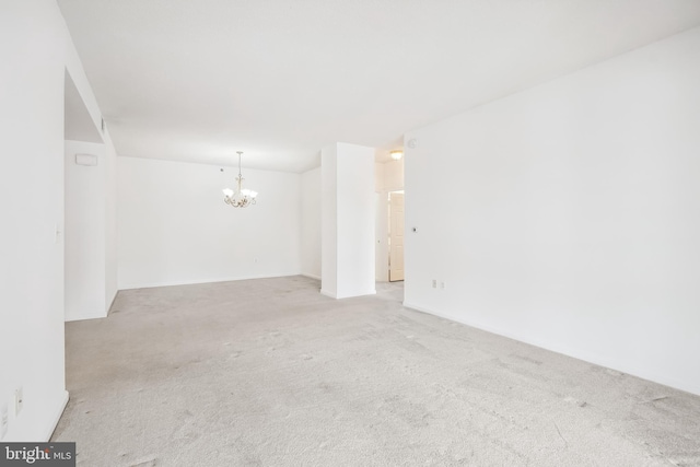 empty room with a chandelier and light carpet