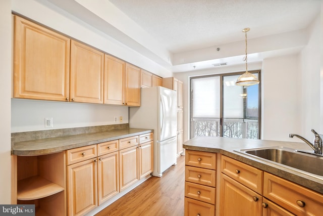 kitchen featuring light brown cabinetry, sink, decorative light fixtures, light hardwood / wood-style flooring, and white refrigerator