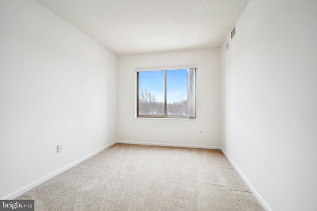 spare room featuring light carpet and a textured ceiling