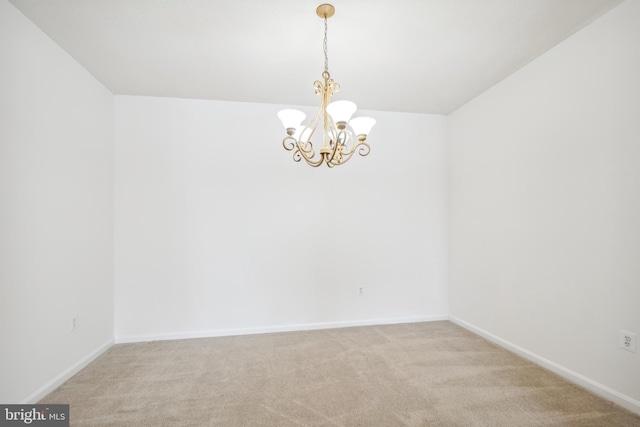 empty room featuring light carpet and a chandelier