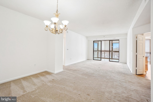 carpeted empty room featuring an inviting chandelier