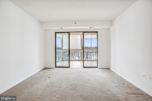 unfurnished room with light colored carpet and a textured ceiling